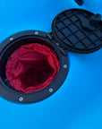 Close-up of the waterproof hatch on the Cambridge Kayaks Neptune single sit-on-top kayak in blue, showing the internal red dry bag for keeping valuables safe and dry during kayaking trips.