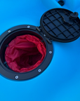 Close-up of the waterproof hatch on the Cambridge Kayaks Neptune single sit-on-top kayak in blue, showing the internal red dry bag for keeping valuables safe and dry during kayaking trips.