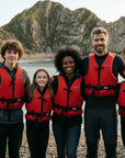 Family wearing Baltic Aqua Pro buoyancy aids in red standing on a beach before kayaking