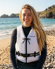Woman standing on a beach wearing Baltic Aqua Pro white canoe buoyancy aid with front zip fastening and adjustable waist strap designed for kayaking, canoeing, and paddle sports safety.