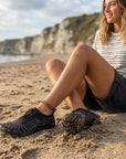 Woman relaxing on beach wearing lightweight water shoes designed for comfort, breathability and summer use