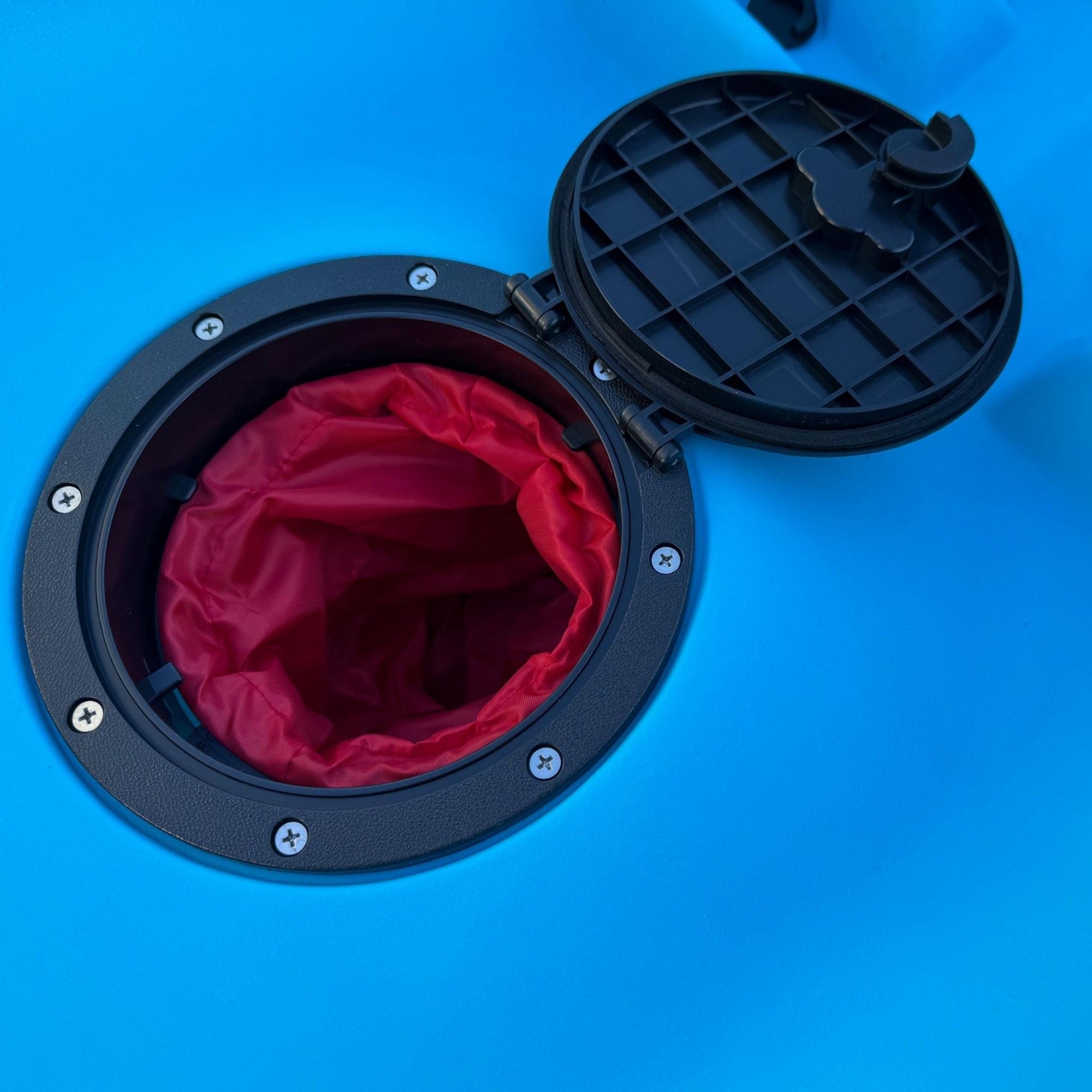 Close-up of the waterproof hatch on the Cambridge Kayaks Neptune single sit-on-top kayak in blue, showing the internal red dry bag for keeping valuables safe and dry during kayaking trips.