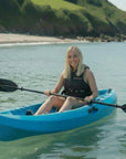 Woman paddling Cambridge Kayaks Neptune single sit on top kayak on calm sea near beach