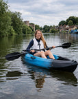 Woman kayaking in Cambridge Kayaks Neptune single sit on top kayak on river near village
