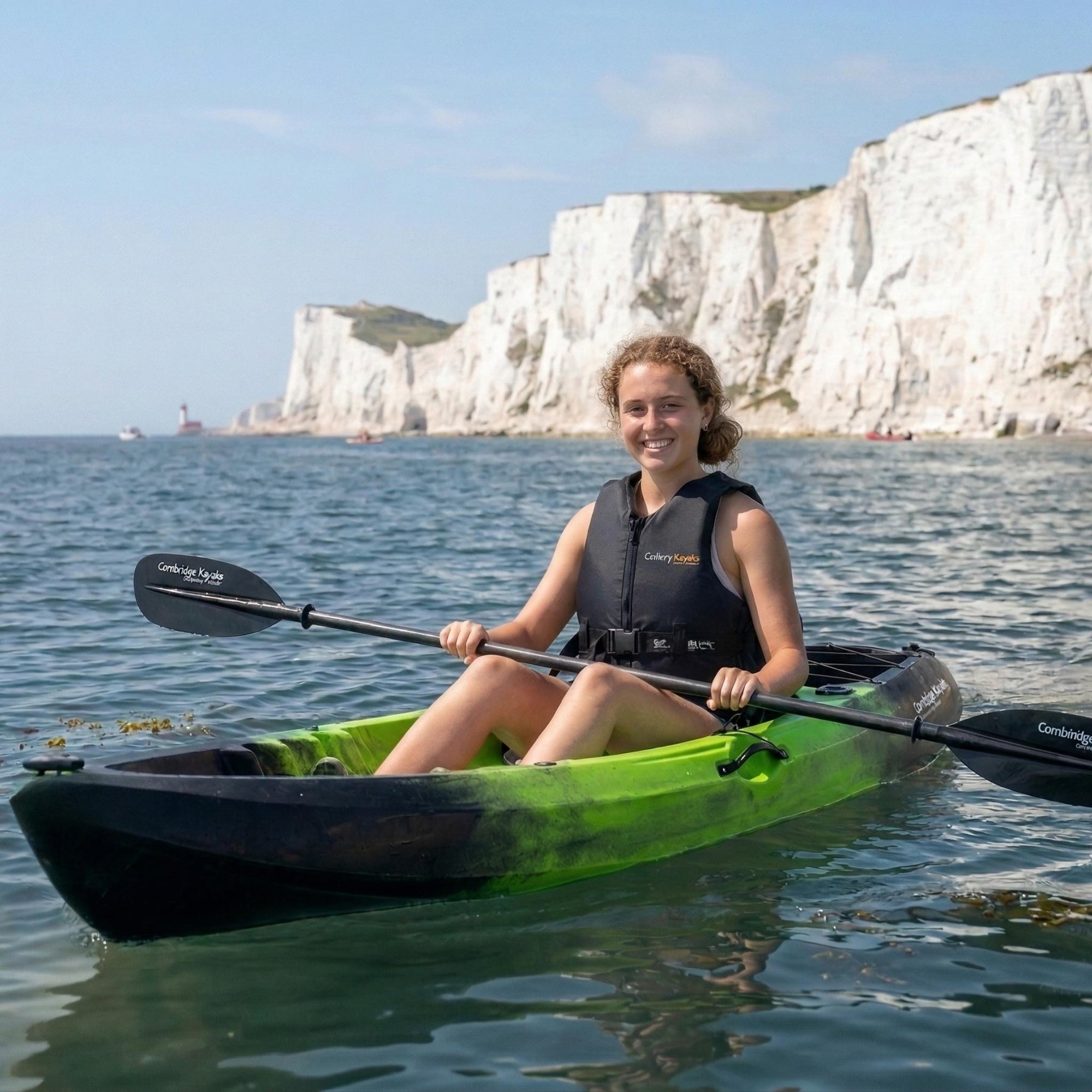 Woman paddling Cambridge Kayaks Neptune single sit on top kayak in clear sea near white cliffs