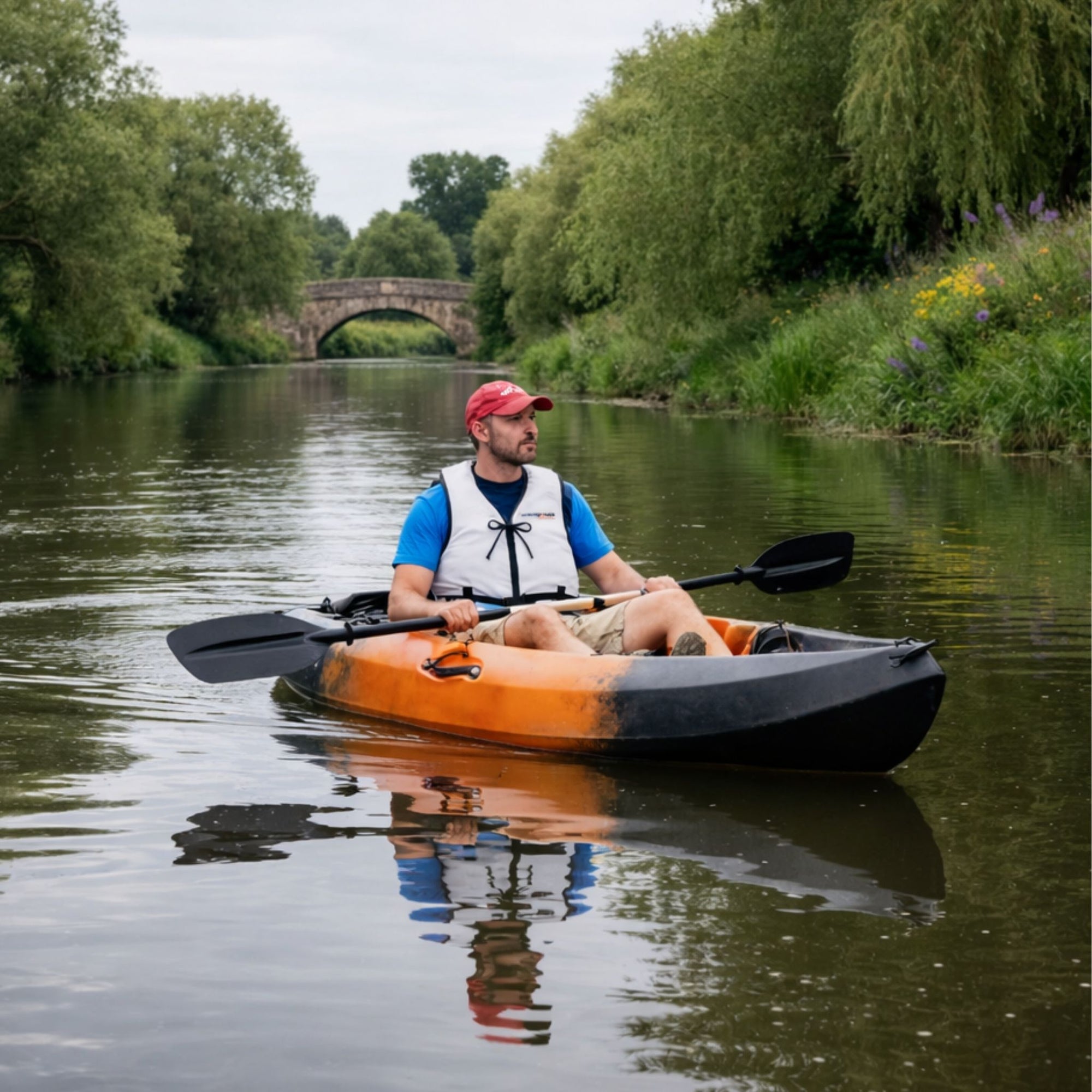 Man kayaking in Cambridge Kayaks Neptune single sit on top kayak on river near stone bridge