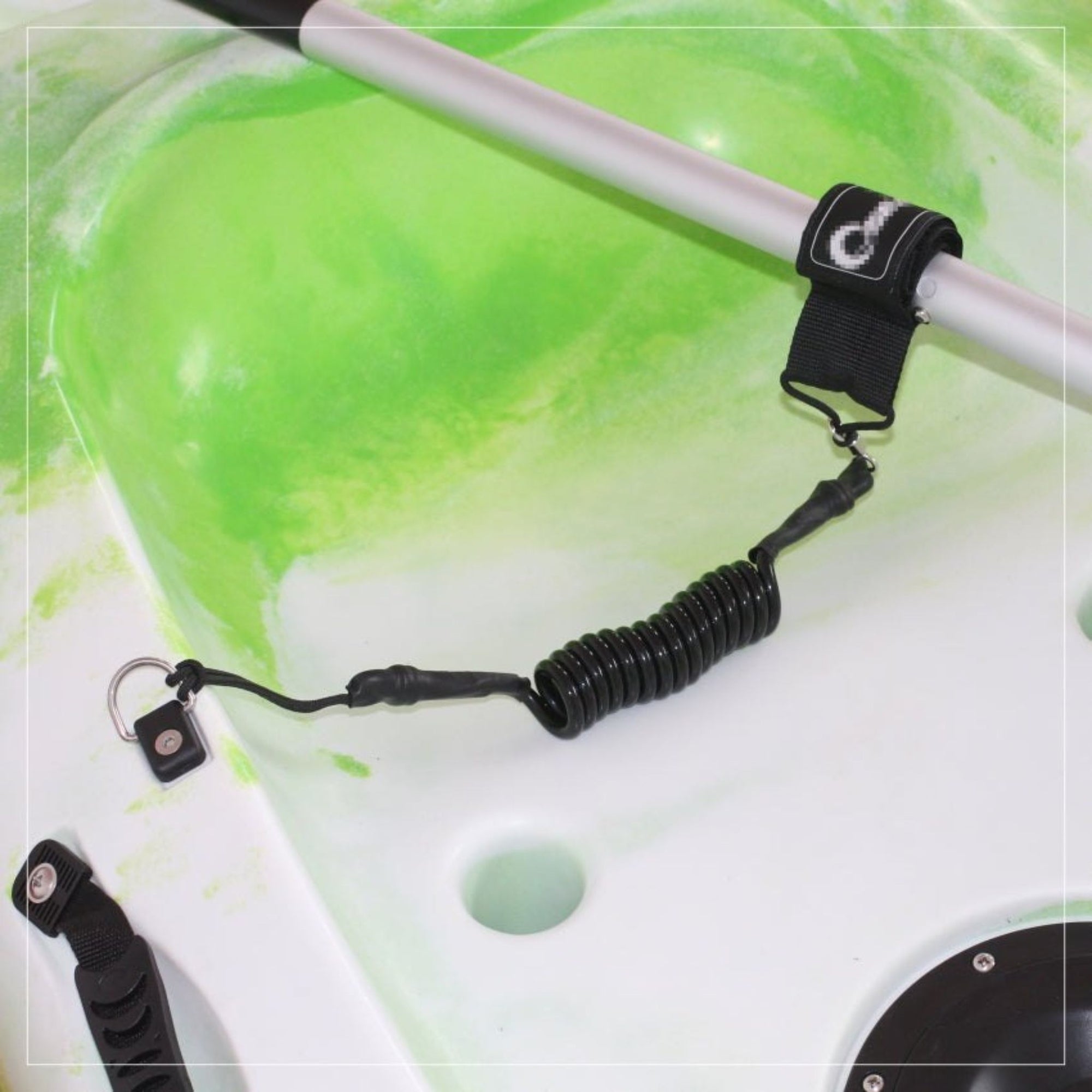 Close-up of Cambridge Kayaks paddle leash connected to a kayak paddle and deck mount, showing secure coiled design in use.
