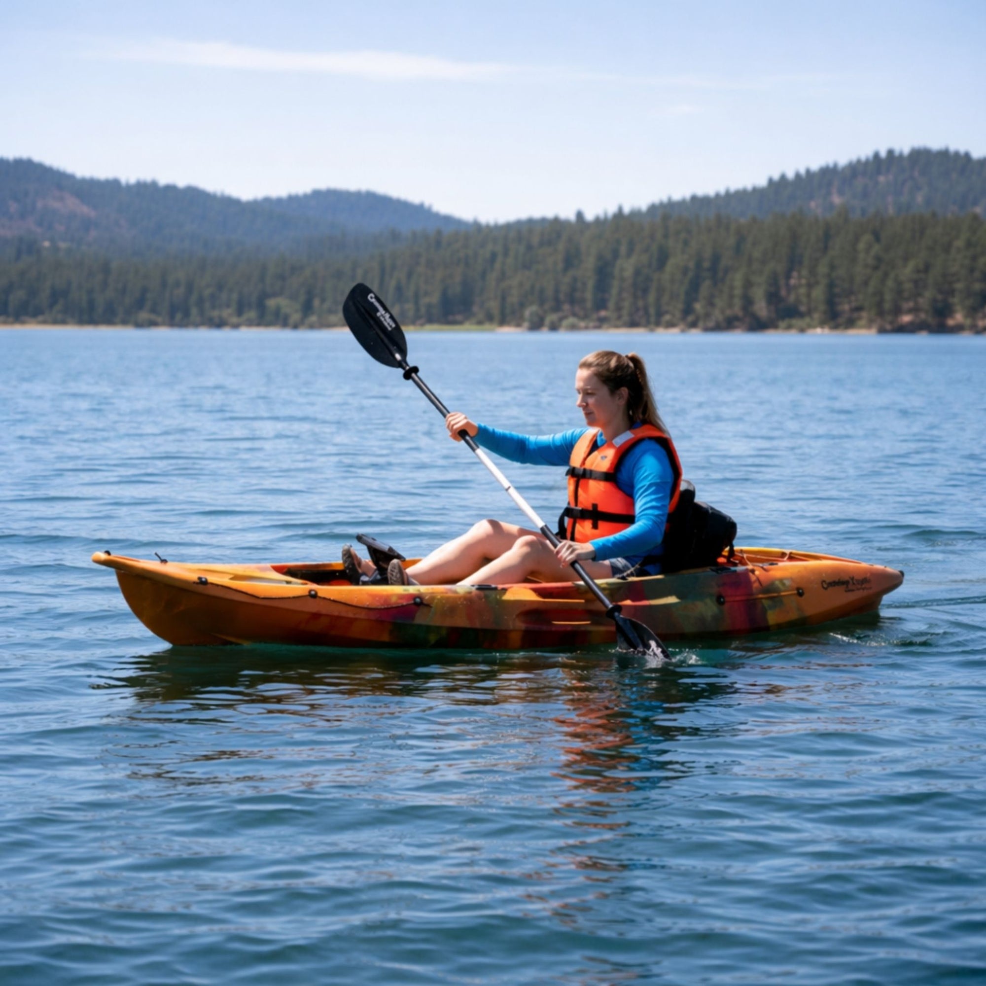 Woman paddling Cambridge Kayaks Quest single 1 plus 1 sit on top kayak on calm lake