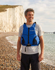 Man wearing blue Cambridge Kayaks buoyancy aid on pebble beach beside the sea