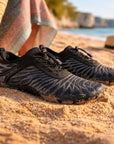 Close up of water shoes on sandy beach showing quick dry material and flexible design for beach and water sports