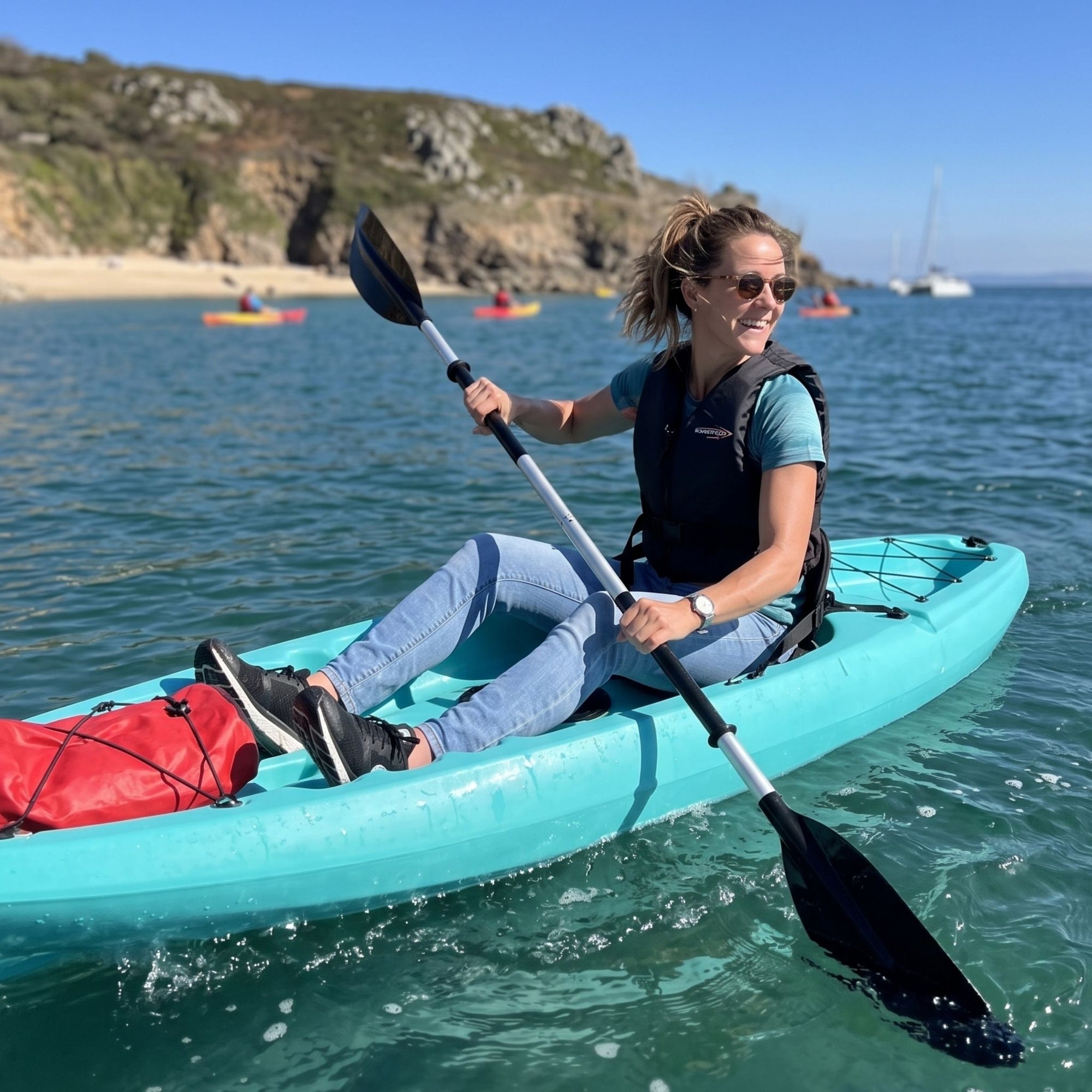 Woman kayaking in single sit on top kayak near beach with calm sea