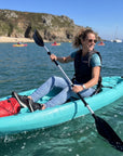 Woman kayaking in single sit on top kayak near beach with calm sea