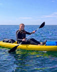 Person paddling single sit on top kayak on open water under blue sky