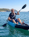 Man paddling single sit on top kayak on calm sea near UK coastline