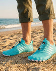 Turquoise water shoes worn on beach showing lightweight design and non slip grip for walking on sand and pebbles