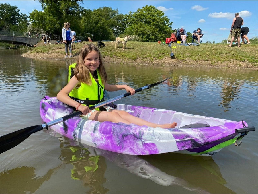 child kayaking in river sitting in a pink and white kayak